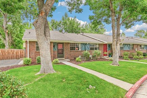 A house with a red door and a green lawn.
